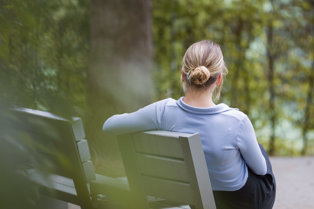 Frau sitzend im Therapiegarten 