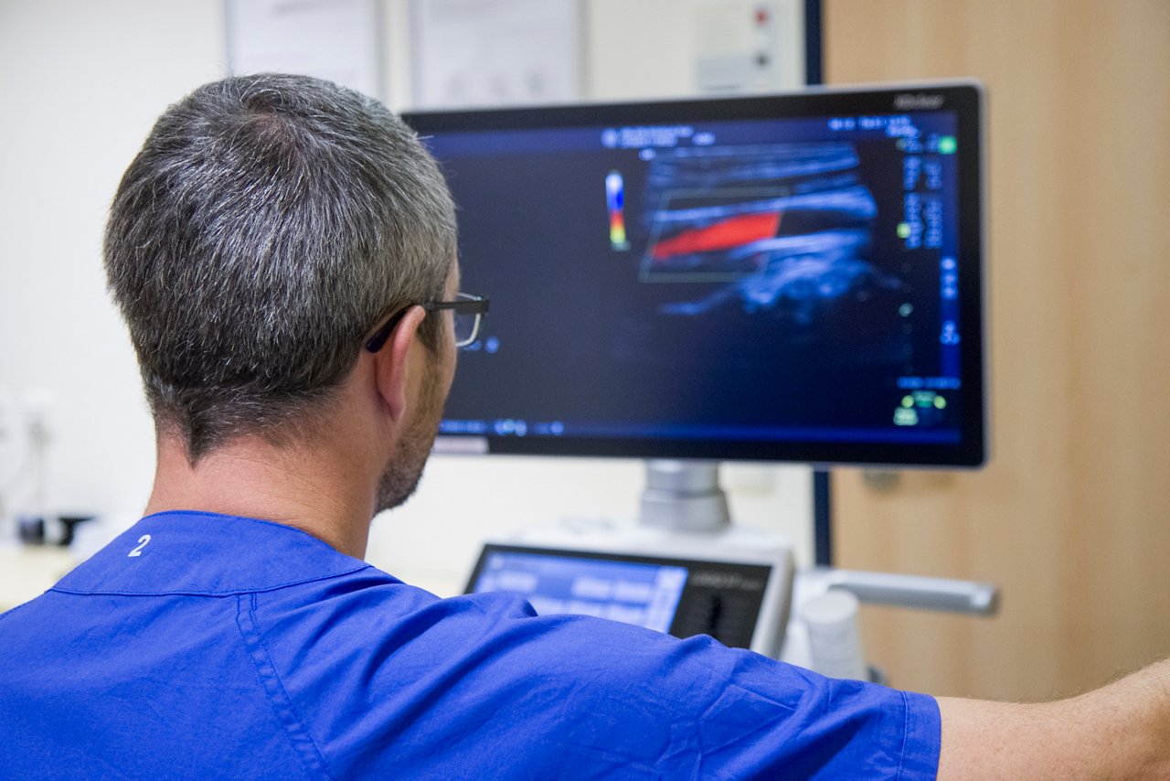 Arzt während einer Ultraschalluntersuchung mit Blick zum Monitor