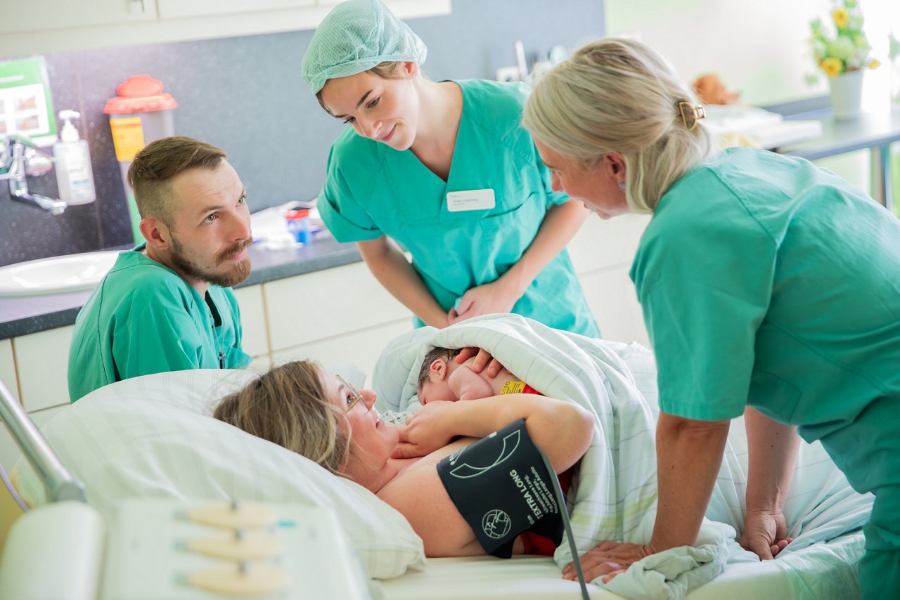 Zwei Hebammen schauen nach junger Familie nach dem Kaiserschnitt