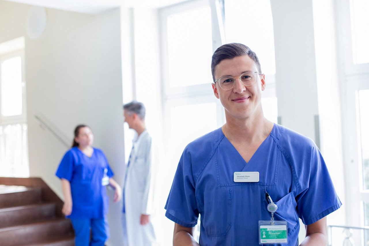Portrait eines Assistenzarztes mit einem Gespräch im Hintergrund 