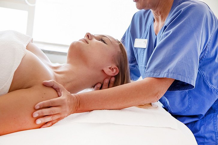 Physiotherapeutin massiert Nacken einer Patientin