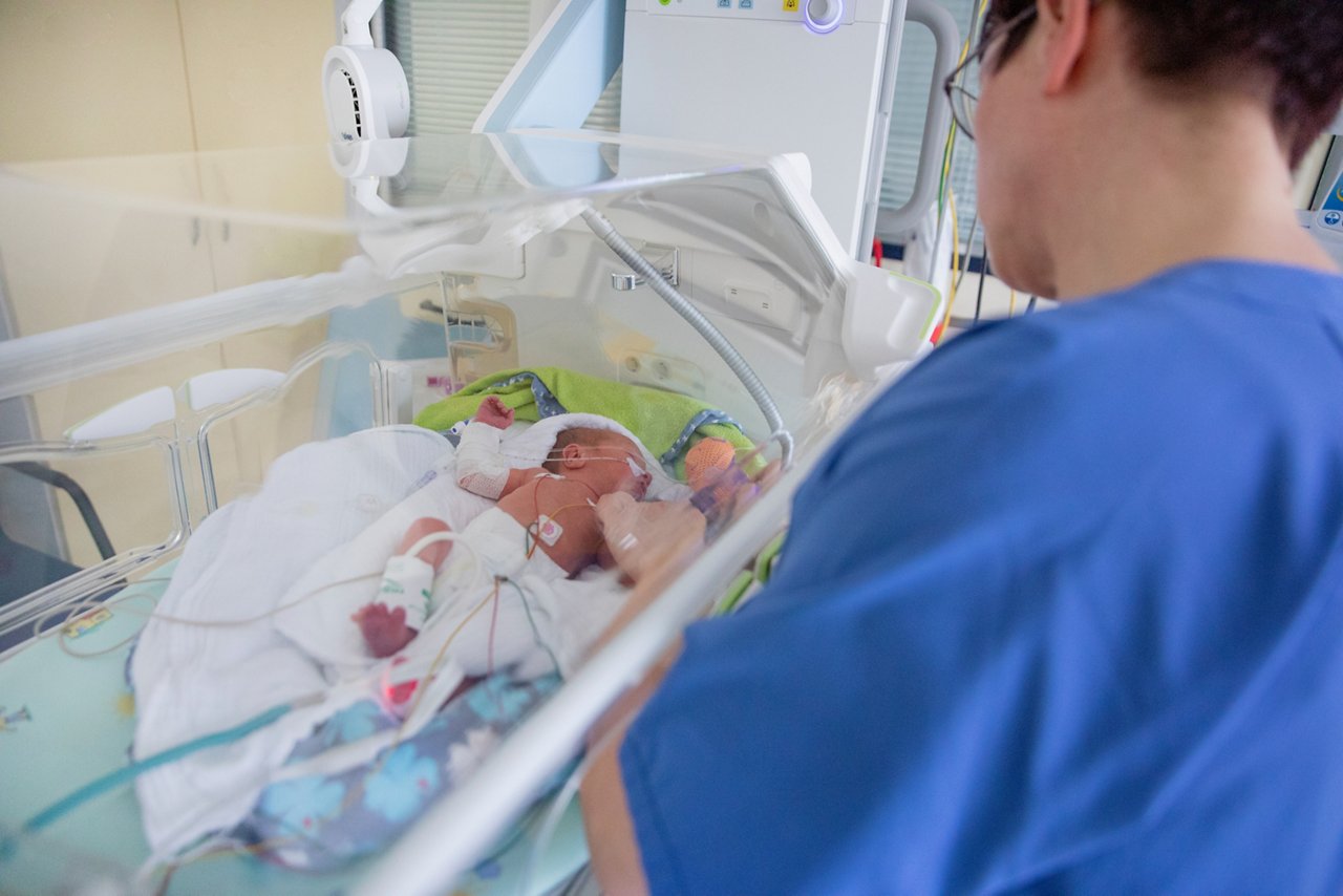Schwester versorgt Frühgeborenes mit Sonde im Inkubator