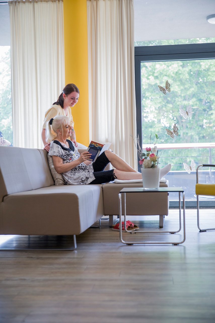 Pflegerin und Patientin schauen gemeinsam in ein Buch