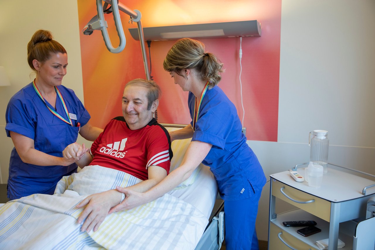 Krankenschwestern lagern einen Patienten im Bett