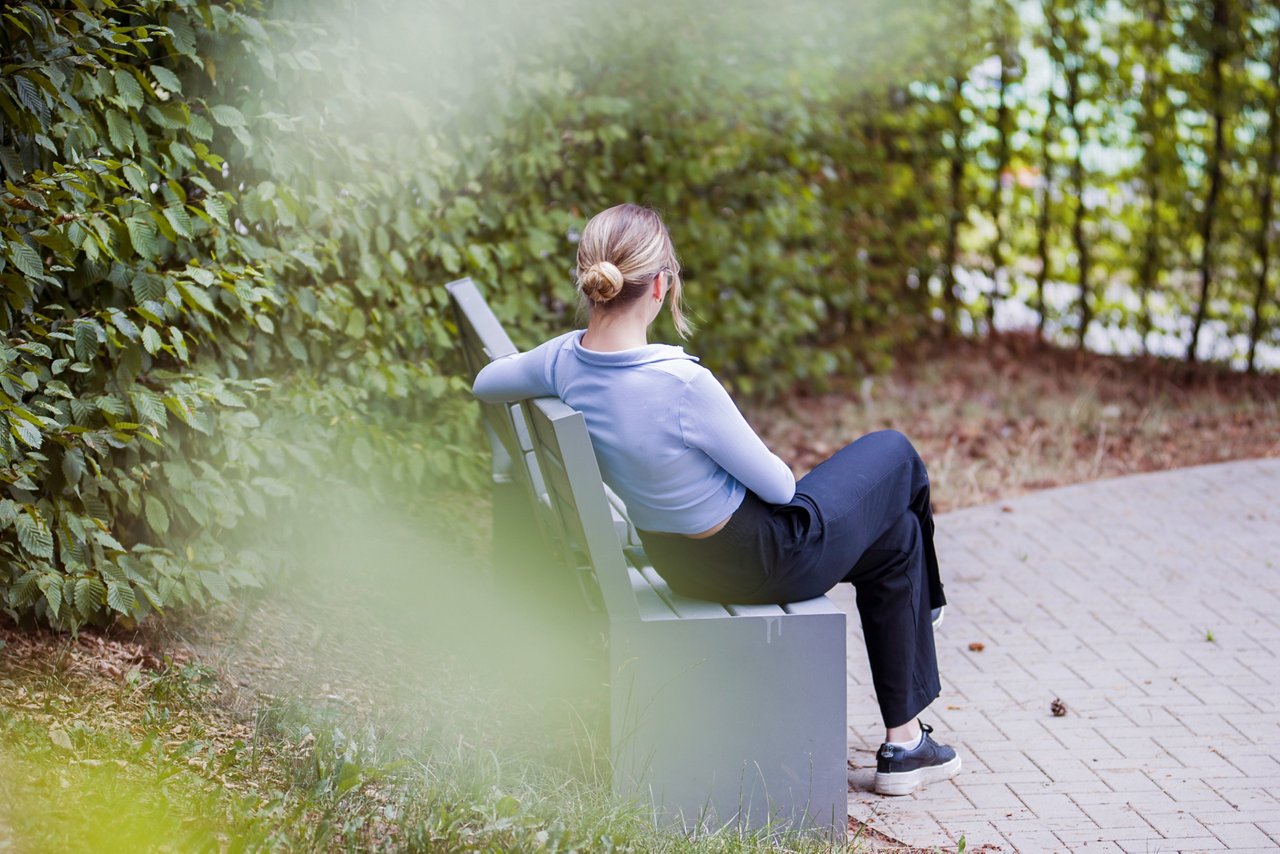 Frau sitzend im Therapiegarten 