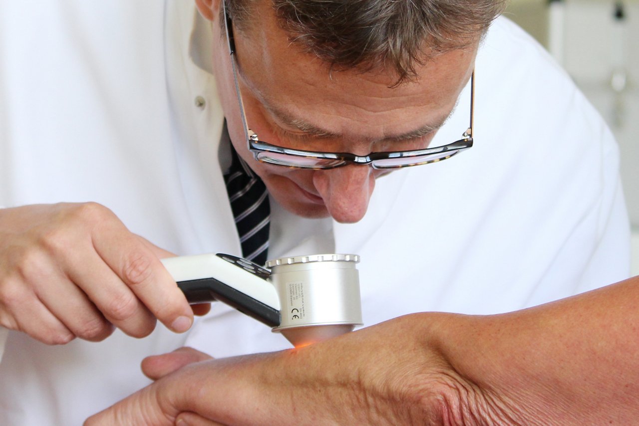 Arzt untersucht Haut mit Dermatoskop 