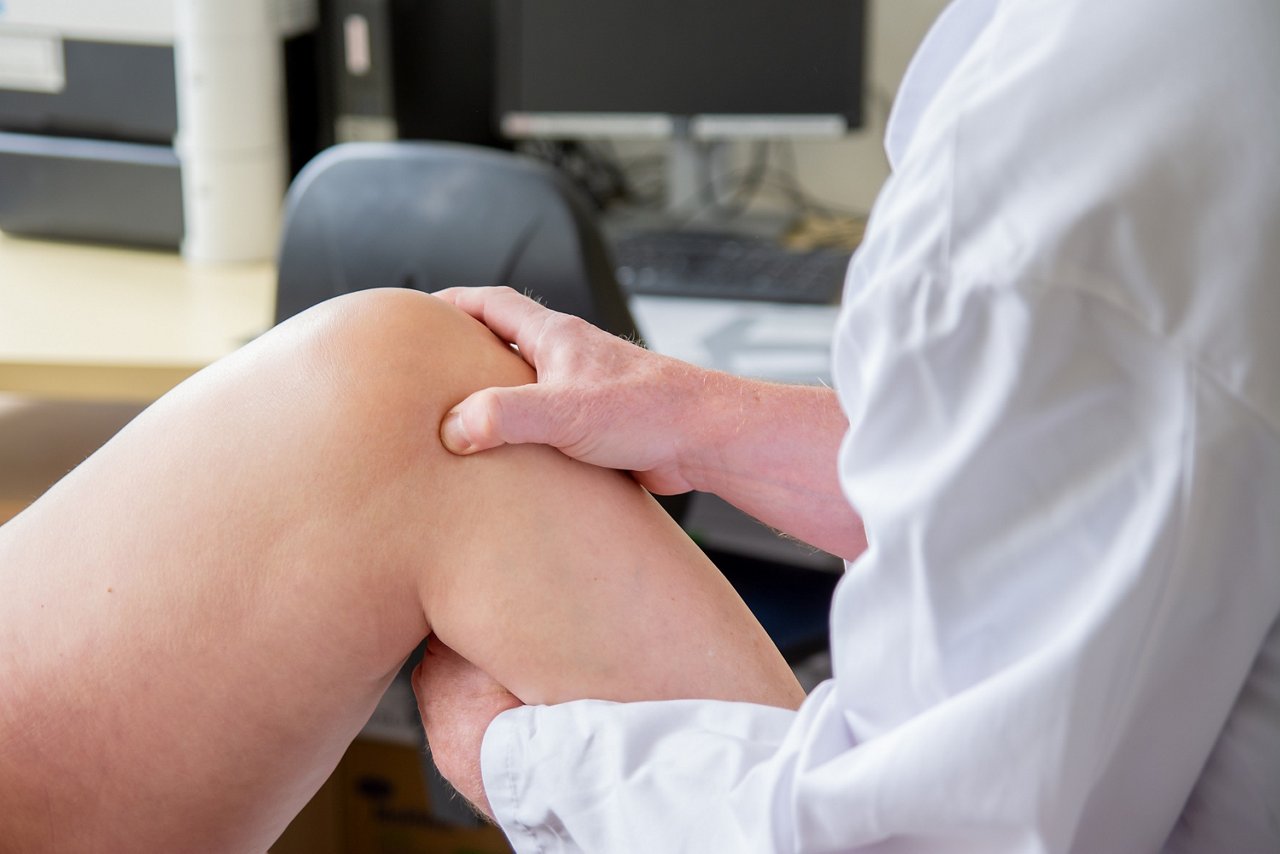 Untersuchung von einem Knie durch den Arzt