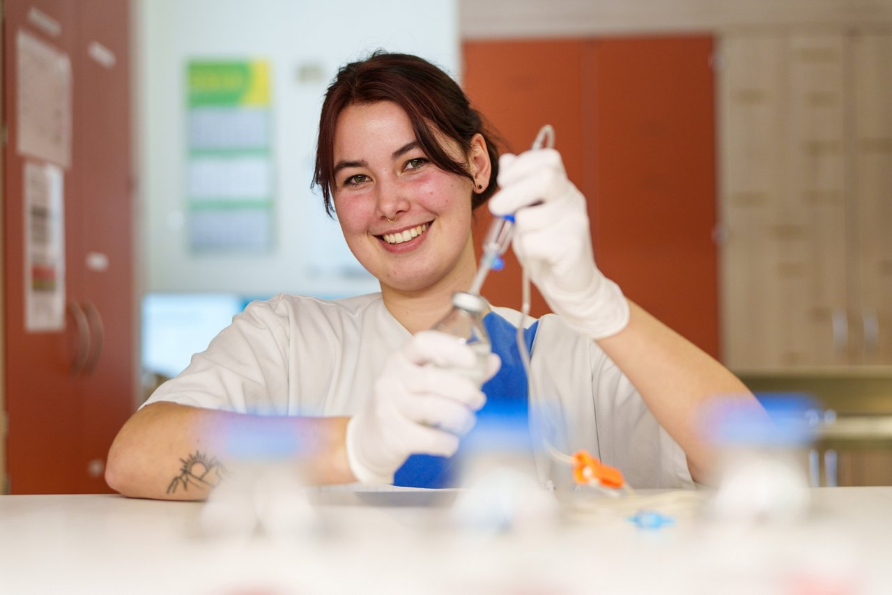 Auszubildende bereitet Infusion vor und lächelt dabei in die Kamera