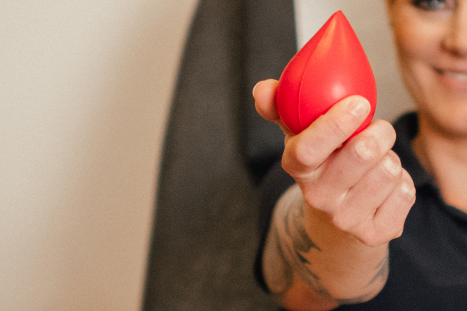 Eine Person hält ein rotes, tropfenförmiges Objekt in der Hand, das für symbolisch für die Blutspende steht.