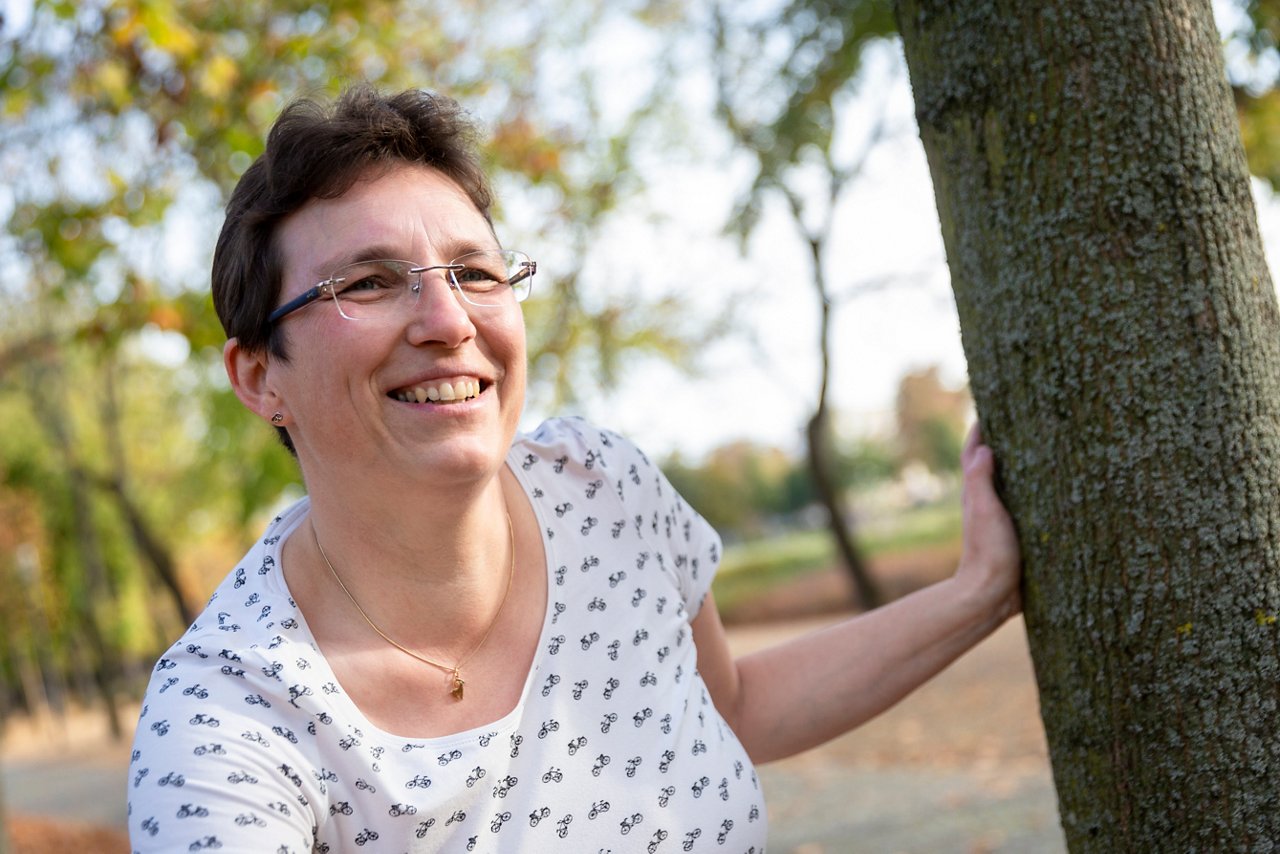 Kollegin auf dem Fahrad am  Baum lehnend
