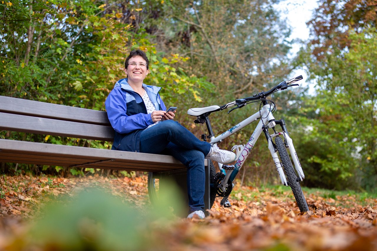 Frau sitzt auf Bank mit Fahrrad