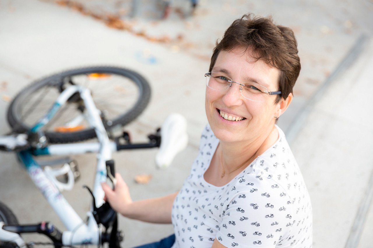 Kollegin auf dem Rad in Kamera blickend