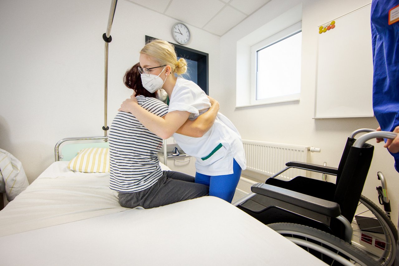 Eine Auszubildende gibt einer Simulationspatientin Hilfestellung