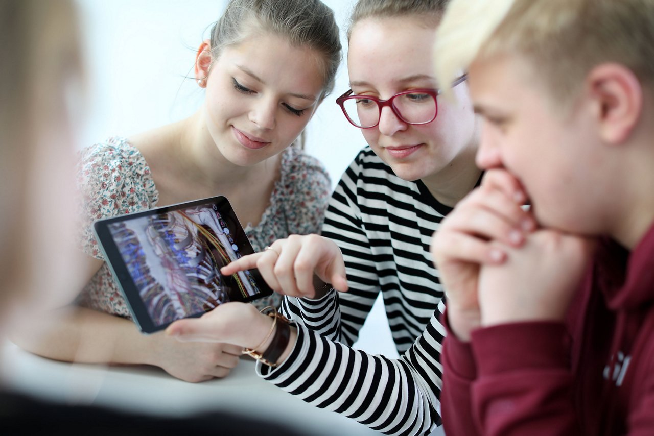 Azubis im Helios Bildungszentrum Berlin schauen auf ein Tablet