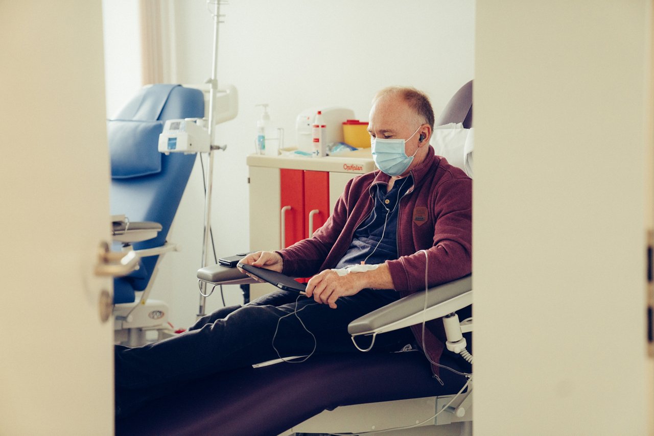 Patient blickt auf sein Tablet während der ambulanten Chemotherapie
