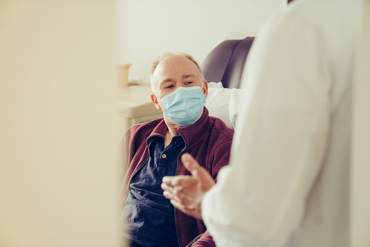 Patient blickt während des Gesprächs auf die Hände des/der Arzt/Ärztin