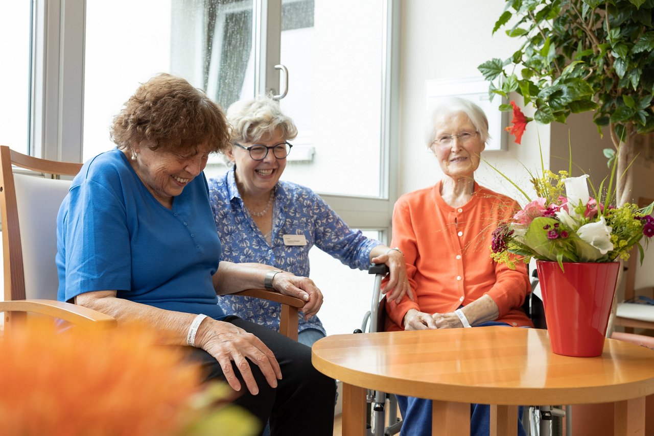 Ehrenamtliche und Patientinnen sitzend am Tisch im Gespräch