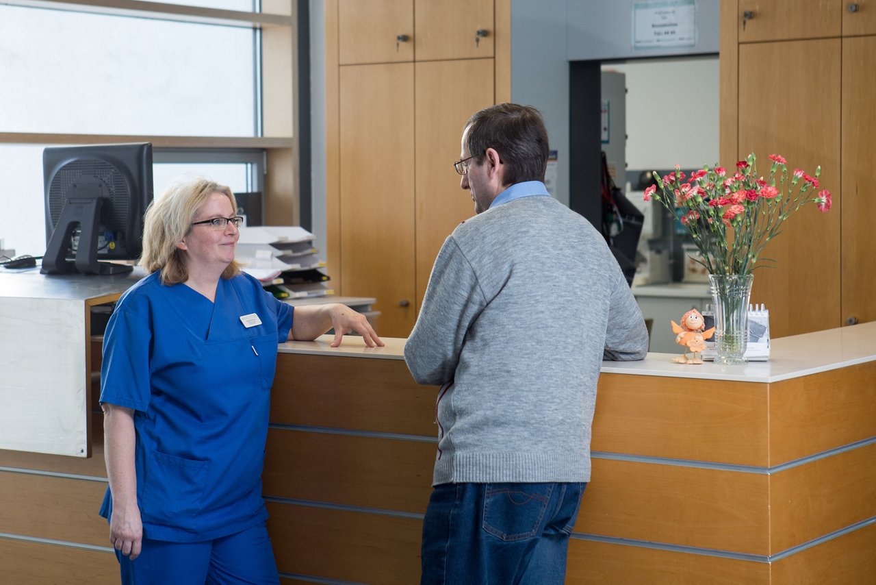 Pflegekraft und Patient im Gespräch auf der Station der Augenheilkunde