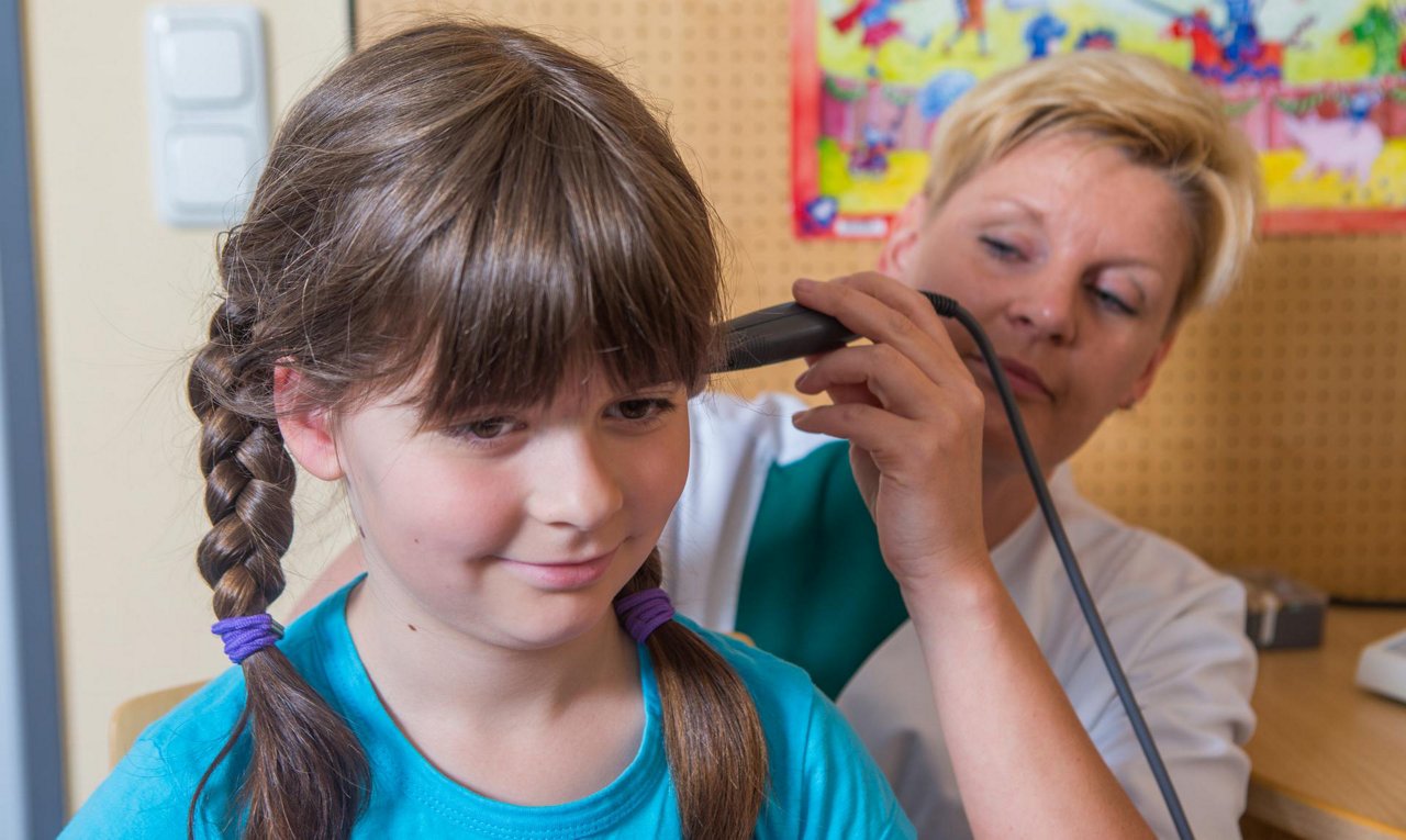 Pflegkraft macht mit Kind Hörtest