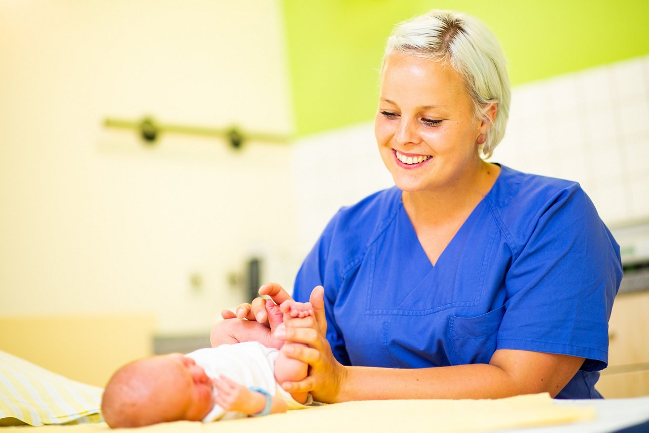 Hebamme mit Baby im Kreißsaal