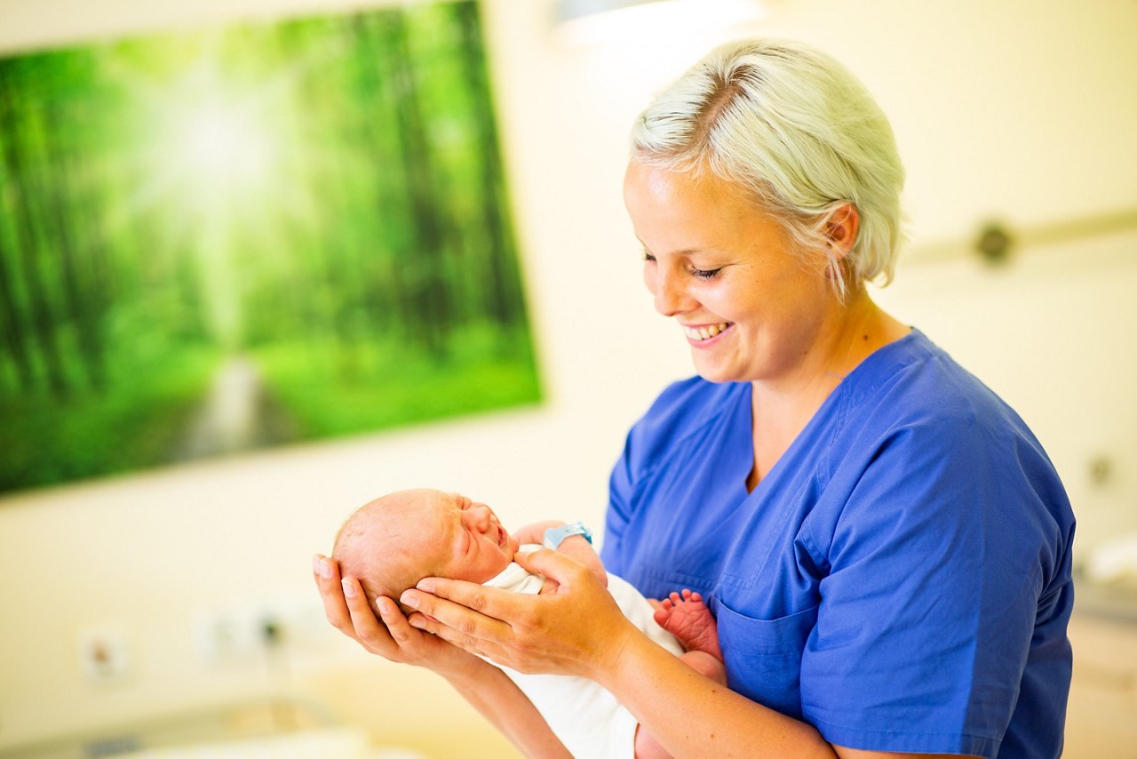 Hebamme mit Baby im Kreißsaal