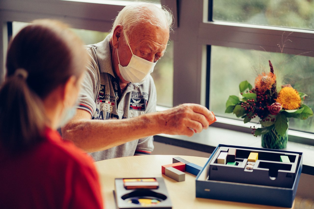 Patient sortiert während der Ergotherapie einen Holzklotz ein