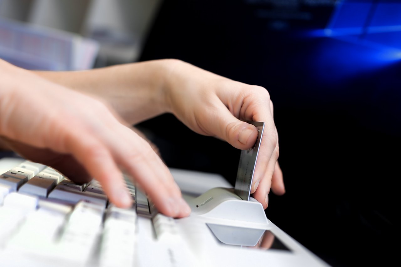 Krankenkassenkarte wird von einer Hand zum Auslesen der Daten in eine spezielle Tastatur gesteckt