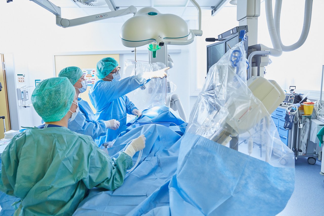 Drei Menschen in OP-Kleidung bei einer Herzkatheteruntersuchung