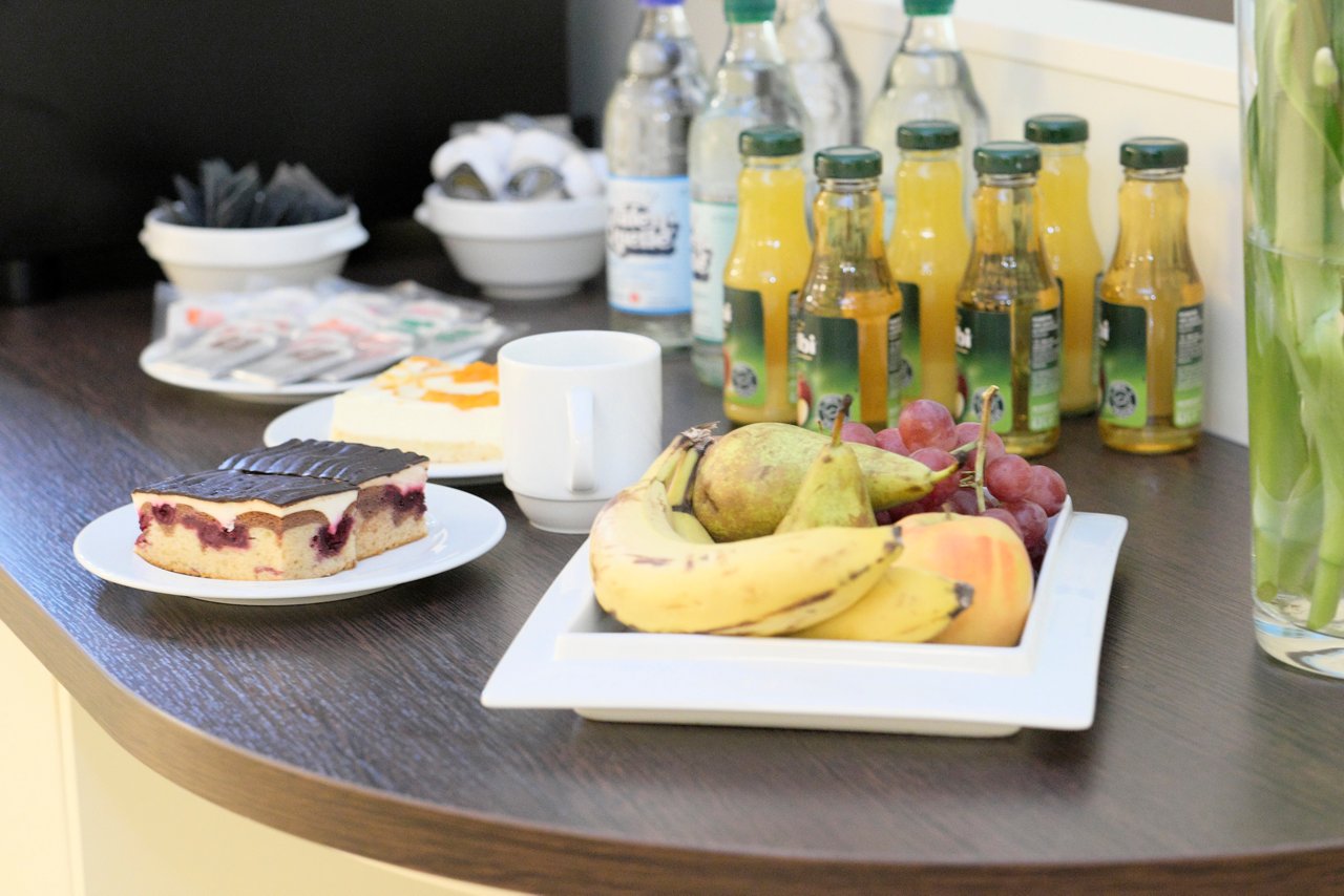 Tisch gedeckt mit Obst, Kuchen, kleinen Flaschen Saft und Wasser