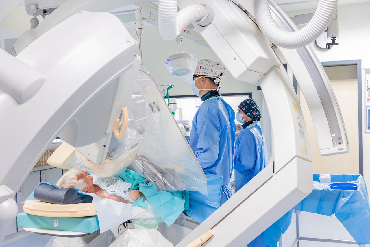 Ein medizinisches Team führt einen Eingriff in einem modernen Operationssaal durch. Der Patient liegt auf dem Tisch, während Ärzte mit präzisen Geräten arbeiten.