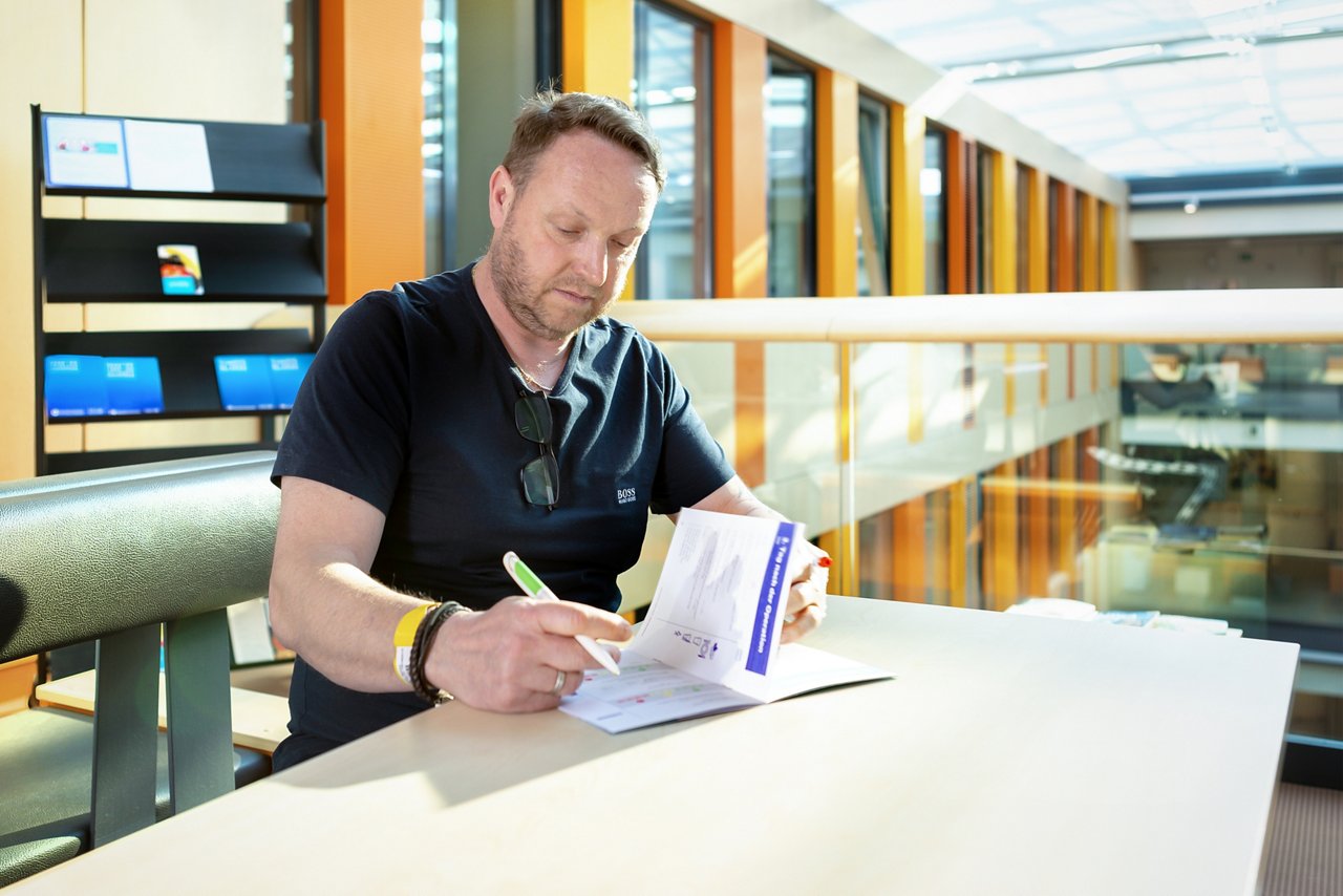 Patient auf Stationsebene sitzend und beim Checklisten ausfüllen