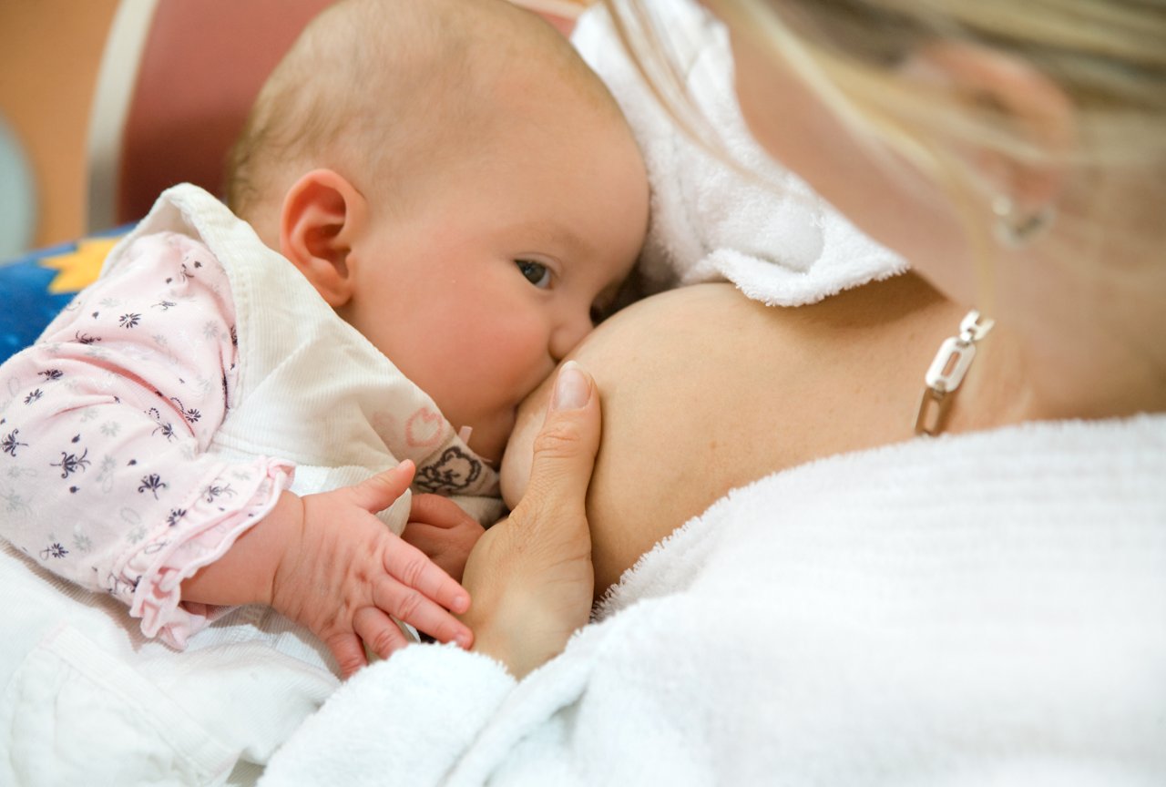 Mutter hält ihr Baby im Arm und stillt es im Wiegegriff