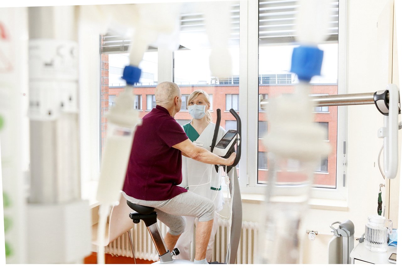 Pflegekraft beim Patienten, der auf dem Ergometer sitzt