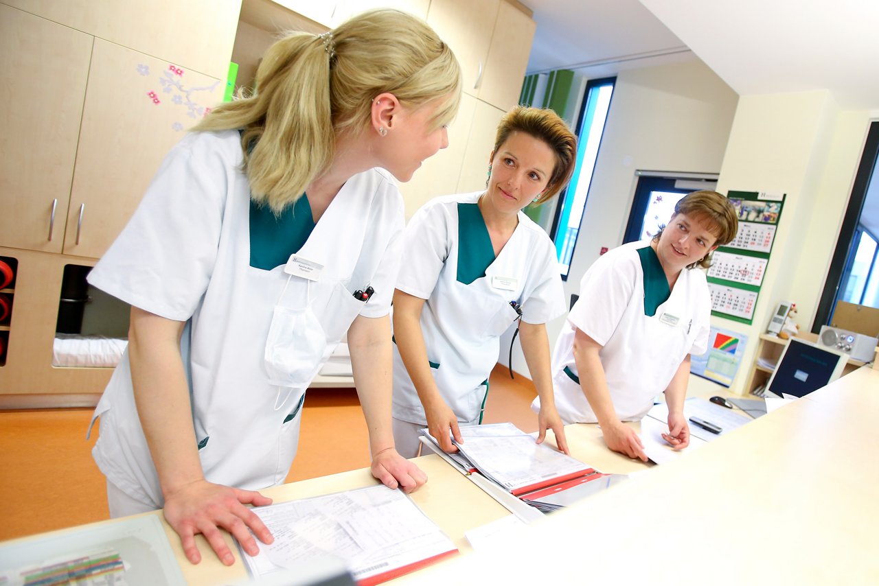 Pflegekräfte hinter dem Stationsstützpunkt während eines Gespräches