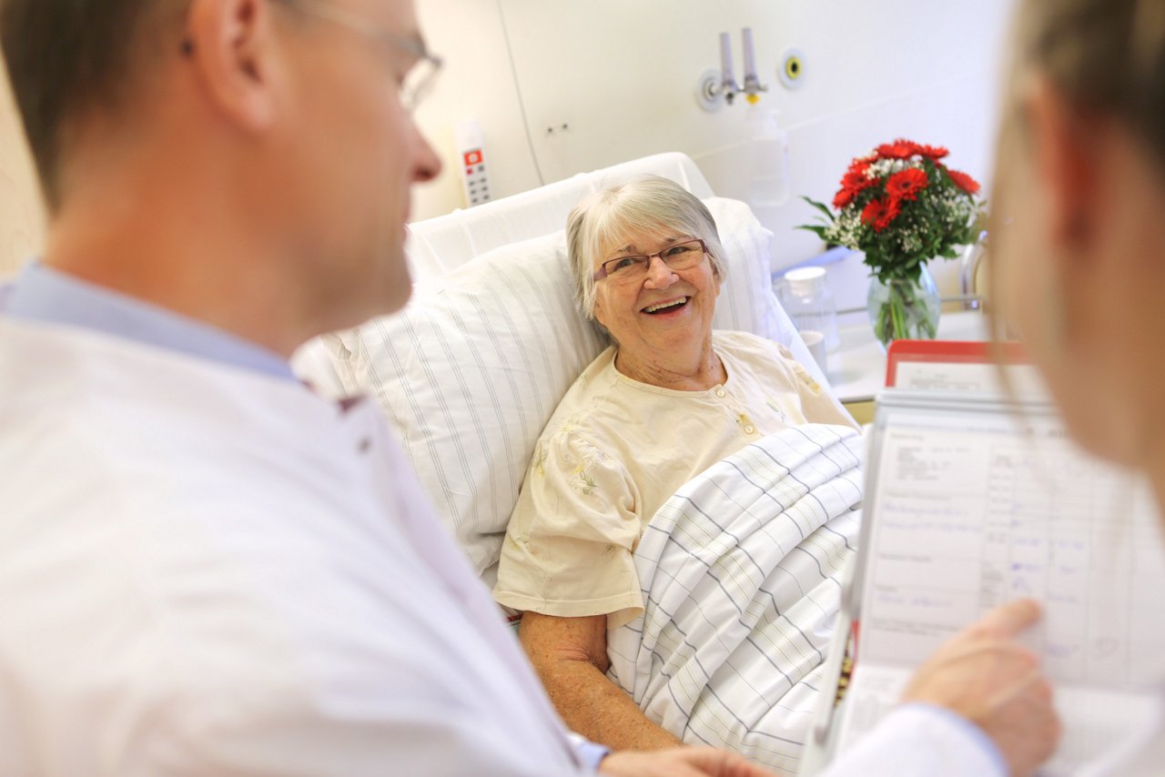 lächelnde Patientin währen der ärztlichen Visite im Patientenzimmer