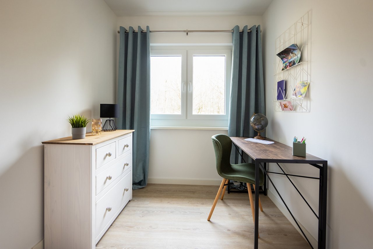 Foto vom Arbeitsbereich im Strandhaus, mit einer Kommode und eine Tisch und Stuhl am Fenster