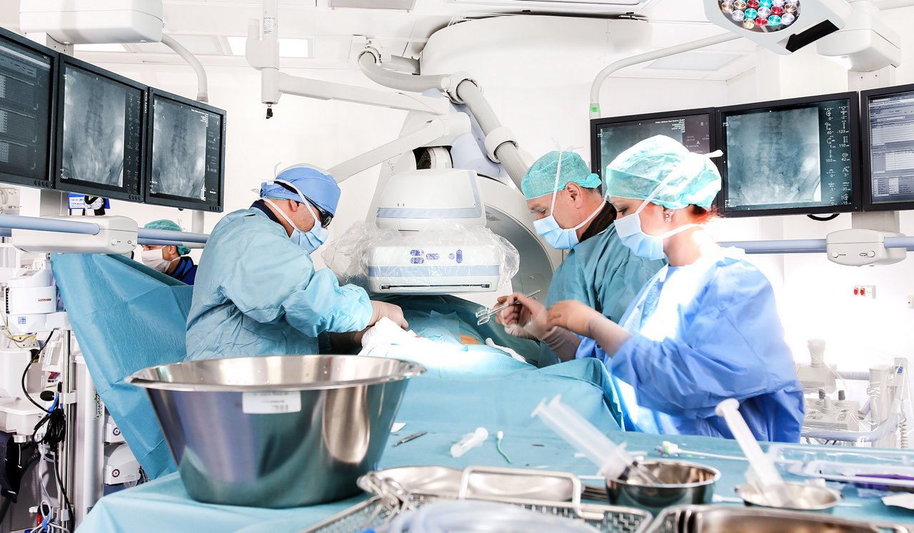 Gefäßchirurgen in einer Operation mit angioskopischen Aufnahmen im Hintergrund 