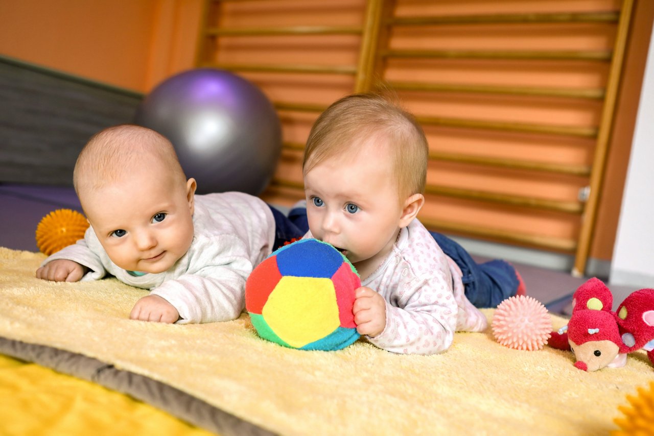 Zwei Neugeborene auf einer Decke mit Spielzeug in der Elternschule 