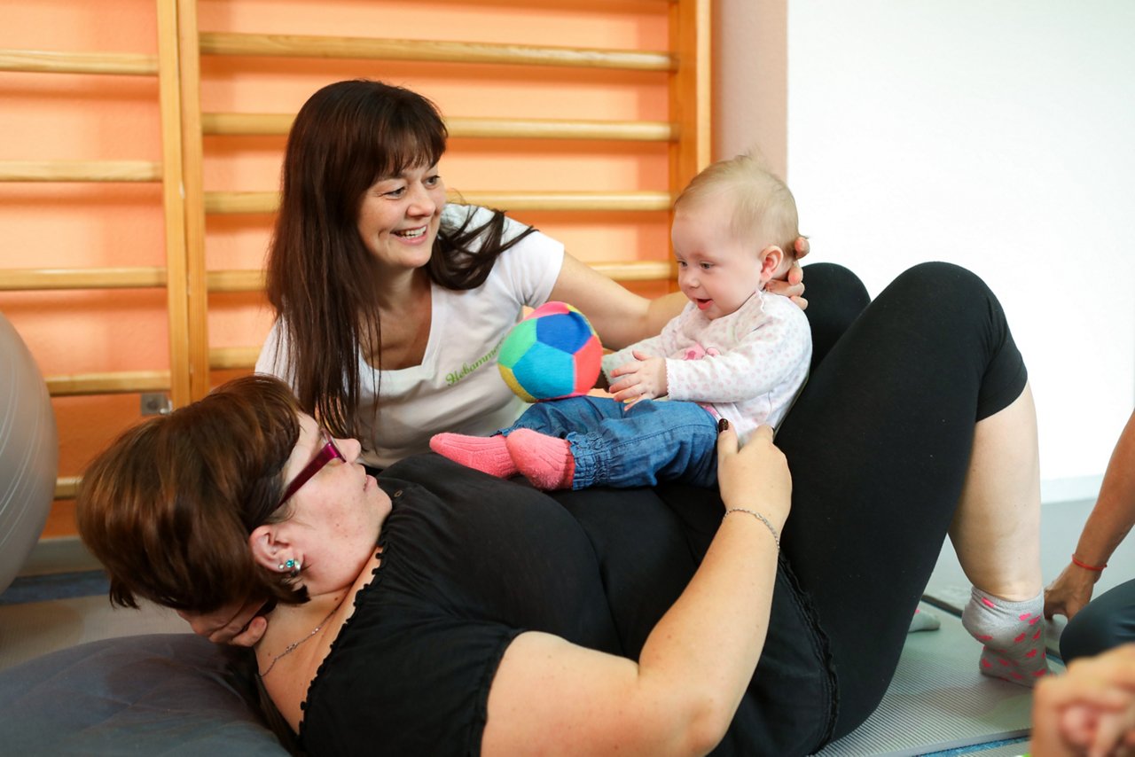 Mutter mit ihrem neugeborenem Kind zusammen mit Stillberaterin in der Elternschule