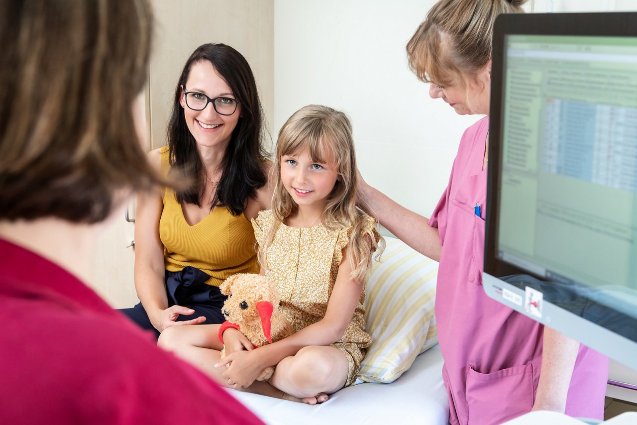 Visite am Patientenbett mit Mutter, Kind und Gesundheit- und Krankenpflegerin 