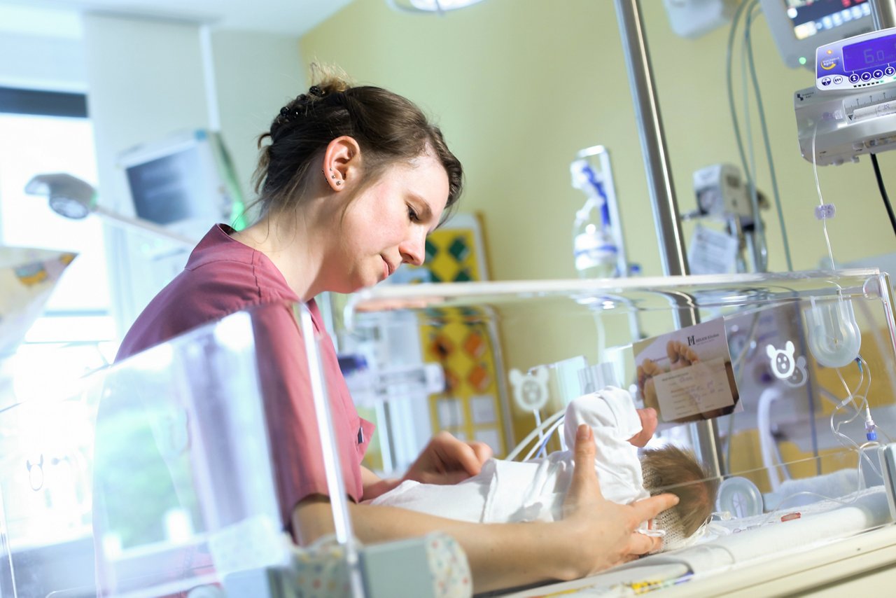 Neonatologieschwester bei der Pflege eines Neugeborenem am Brutkasten