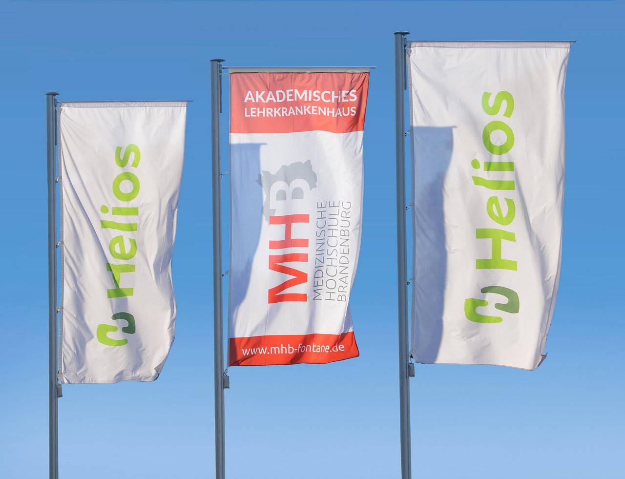 Flaggen mit dem Logo der Helios Kliniken und des Akademisches Lehrkrankenhaus der Medizinischen Hochschule Brandenburg Theodor Fontane (MHB)