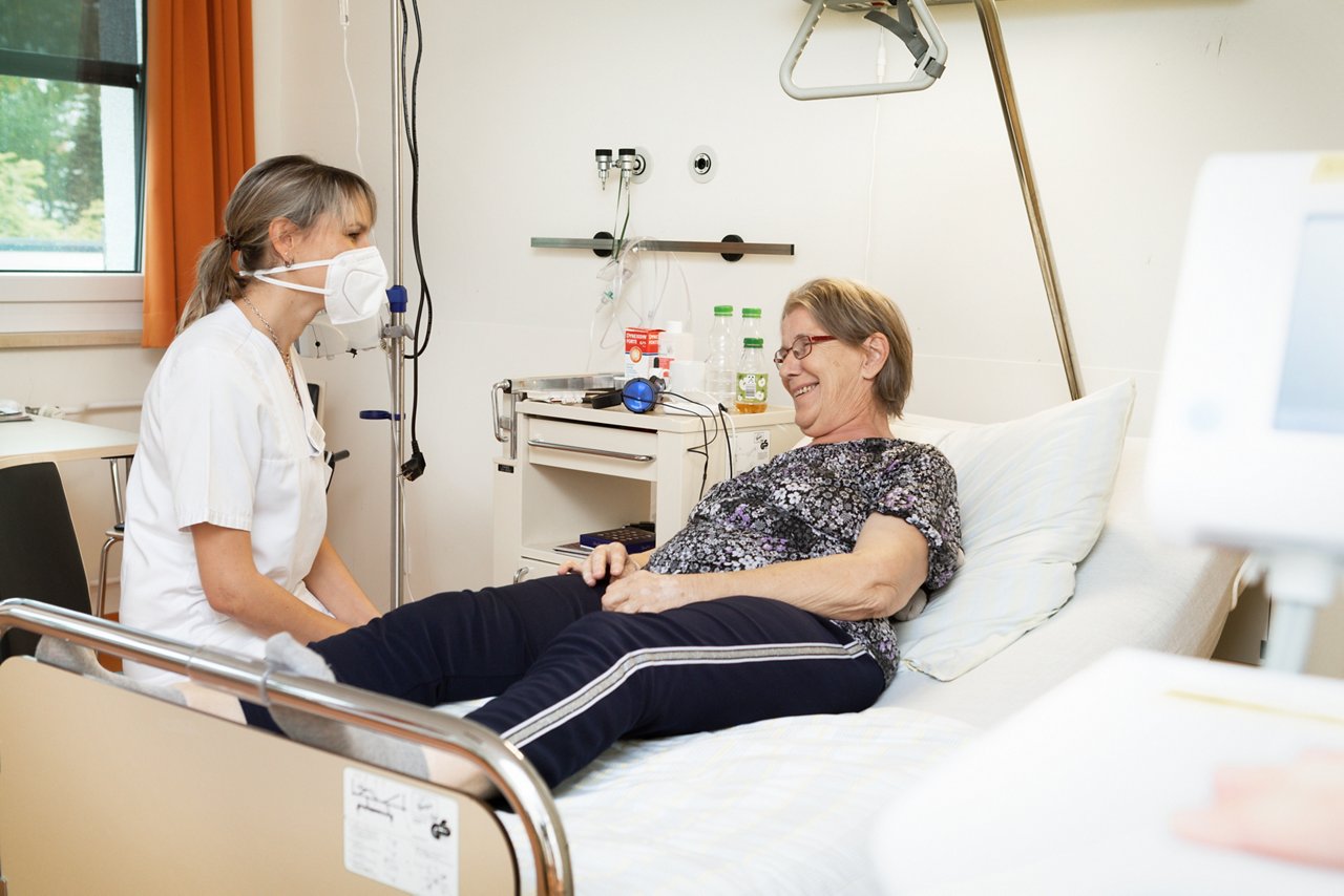 Ärztin und Patientin führen eine Unterhaltung am Bett auf der Onkologiestation