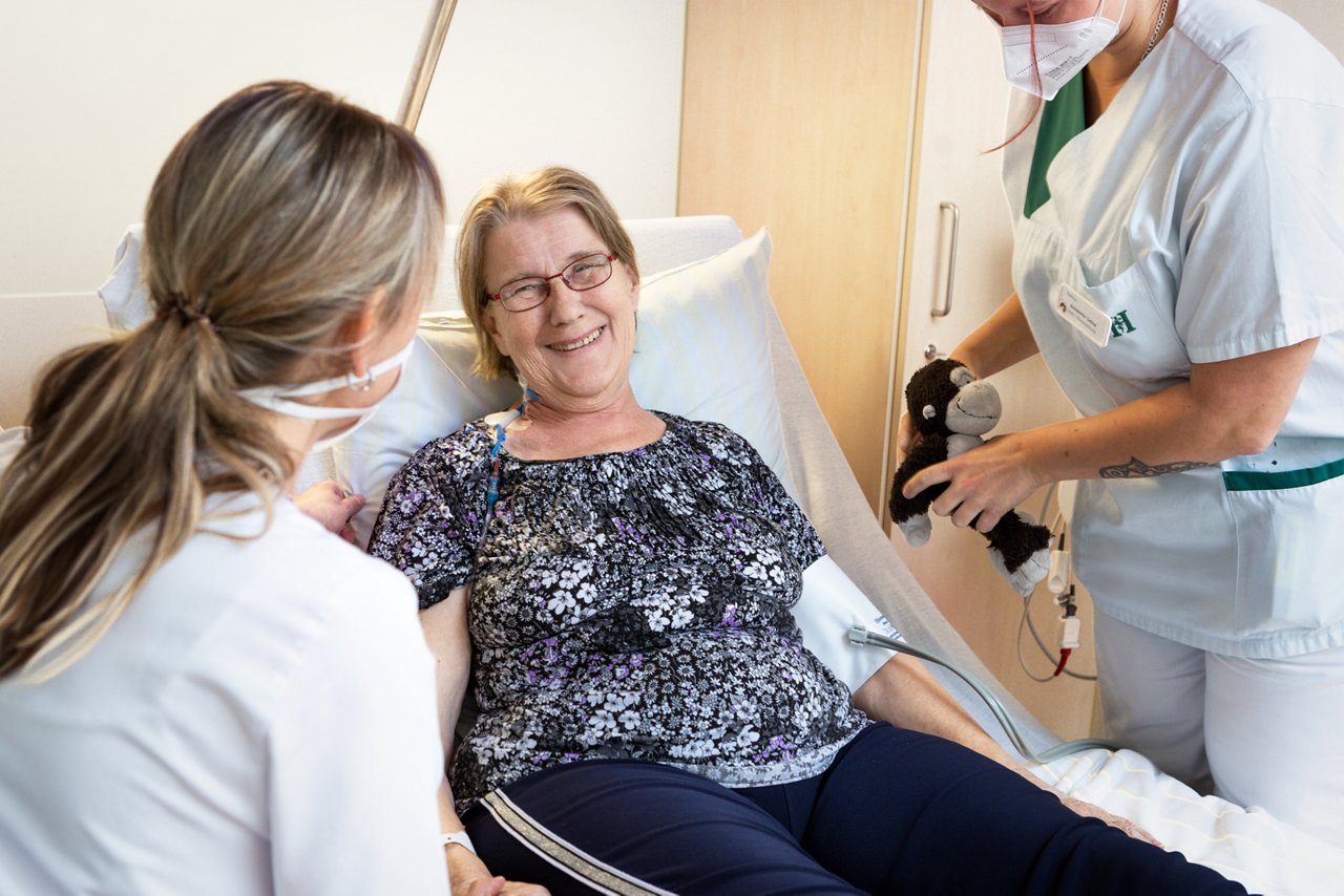 Onkologiepatientin bekommt im Bett eine Therapie unter Beobachtung einer Ärztin und Pflegeschwester