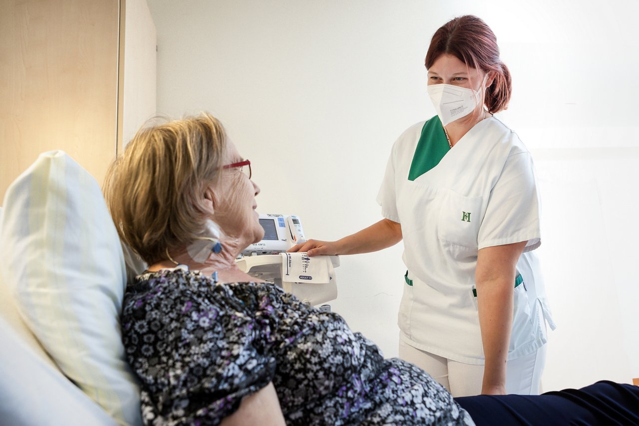 Gesundheits- und Krankenpflegerin bei der Pflege an einer Patientin der Onkologie
