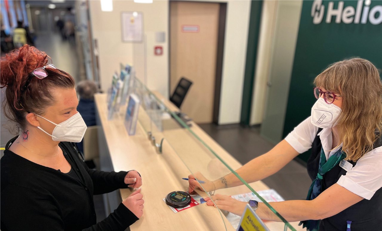 Empfangsmitarbeiterin übergibt Pager an Patientin