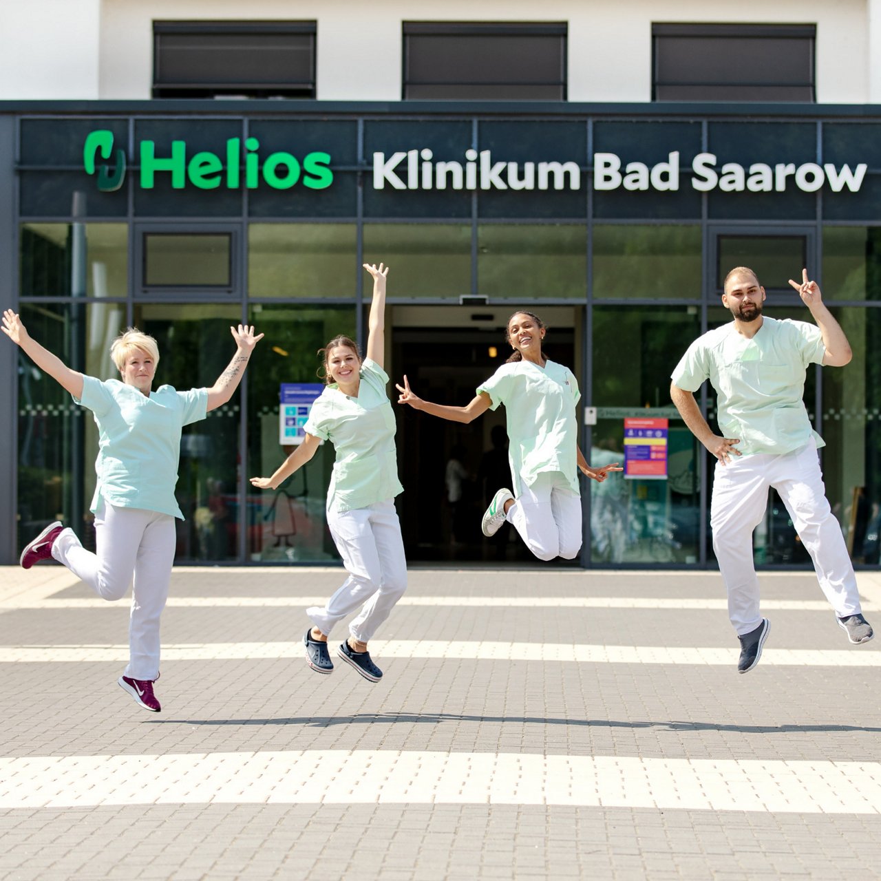 Auszubildende der Pflege springen fröhlich über den Abschluss hoch