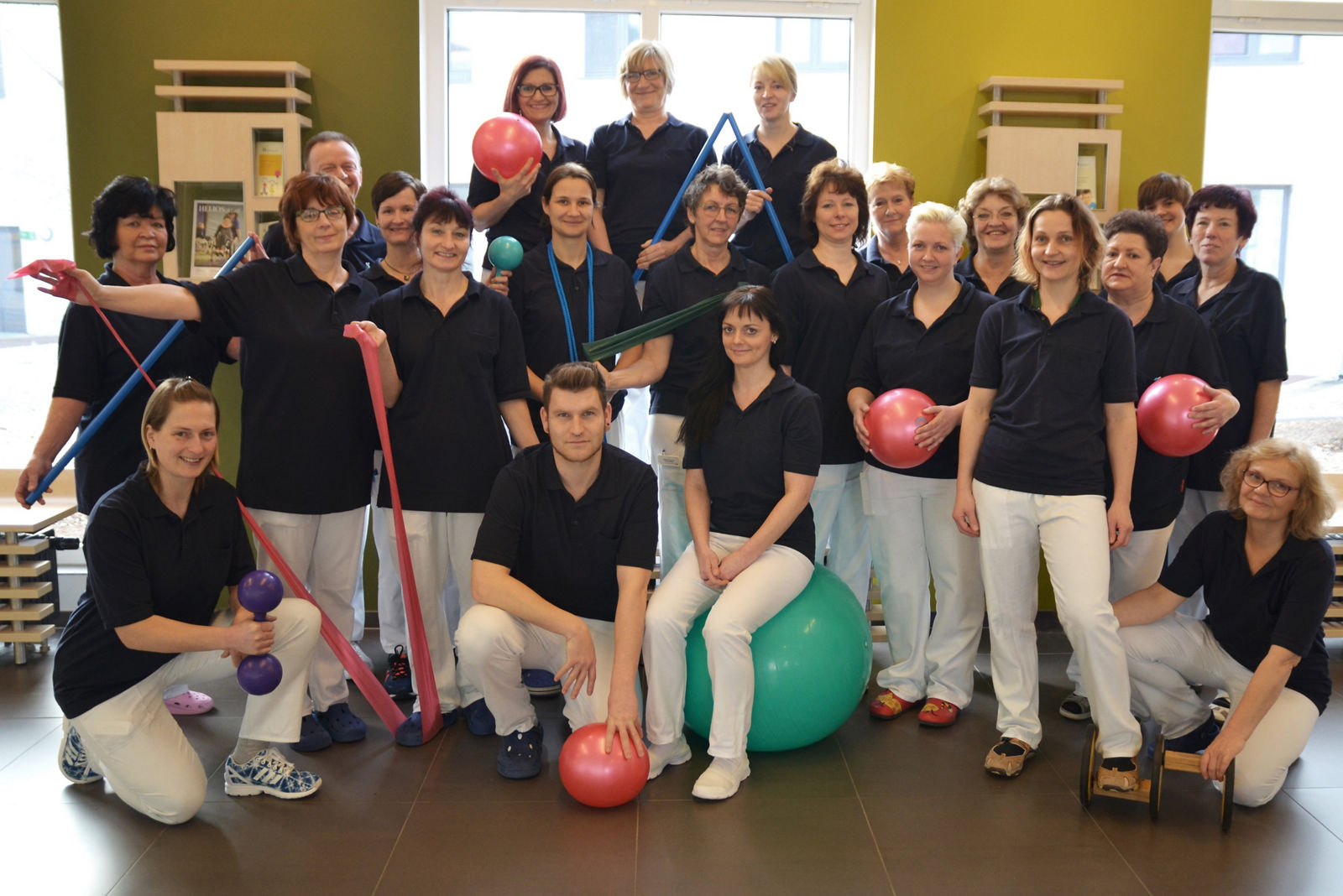 Das Team der Physiotherapie im Klinikum Bad Saarow, die Mitarbeitenden haben Therabänder und Gymnastikbälle in der Hand