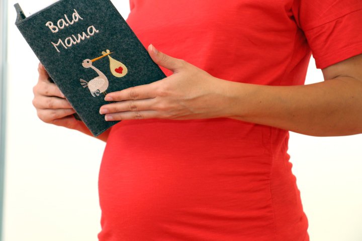 Schwangere mit Mama Heft und Babybauch