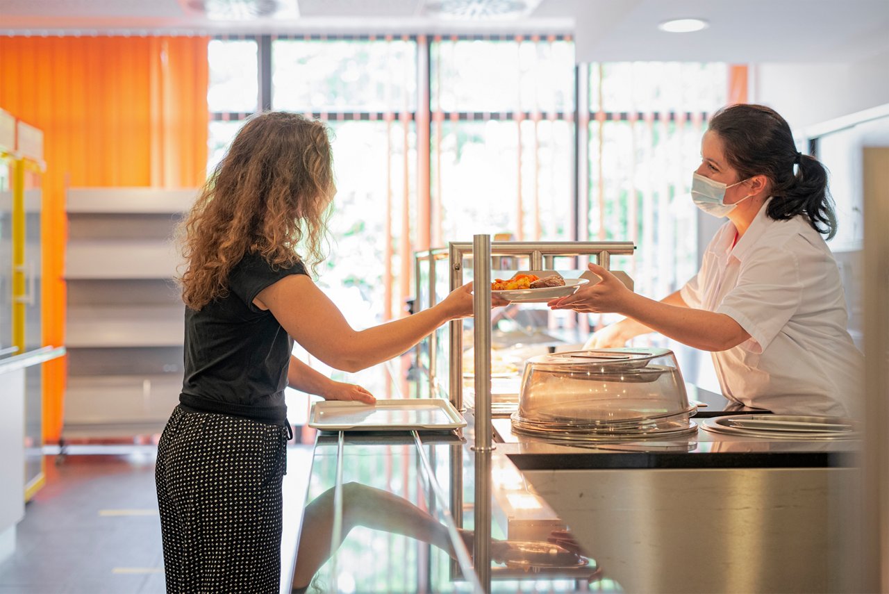 Frau an der Essensausgabe der Cafeteria